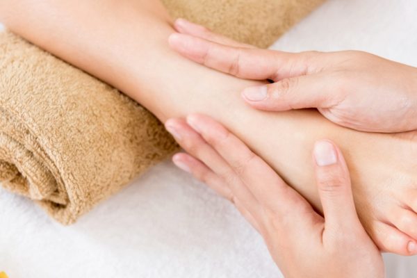 Professional therapist giving relaxing reflexology Thai foot massage treatment to a woman in spa - panoramic banner