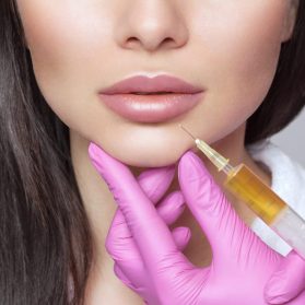Cosmetologist does prp therapy anti wrinkle and aging skin on the chin and on the face of a beautiful woman in a beauty salon. Cosmetology concept.